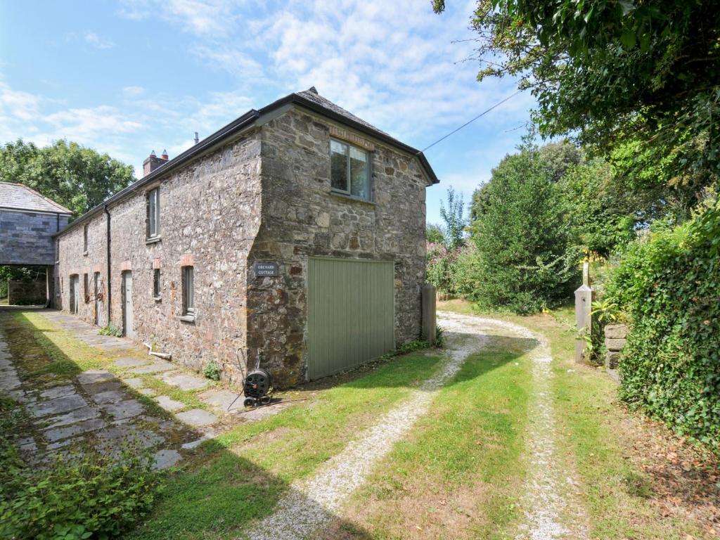 an old stone house with a green garage at Orchard Cottage in Saint Endellion