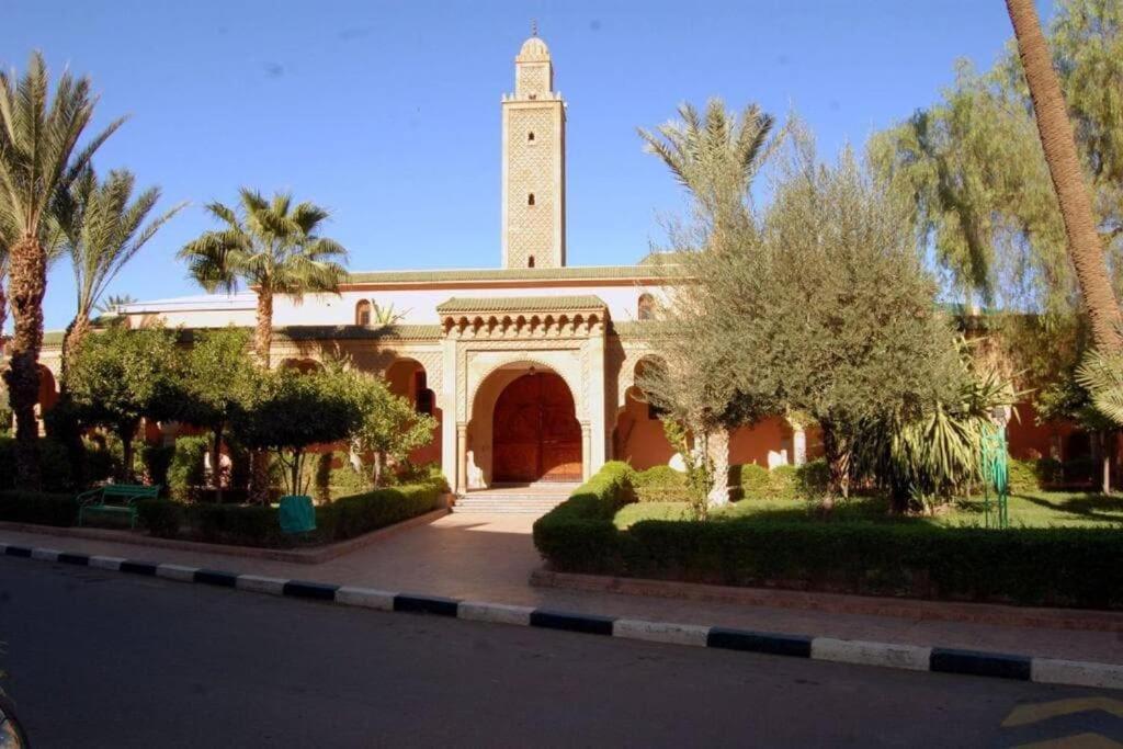 Riad kech residence al Qarya syahiya Marrakech في مراكش: مبنى فيه مسجد مع برج الساعة