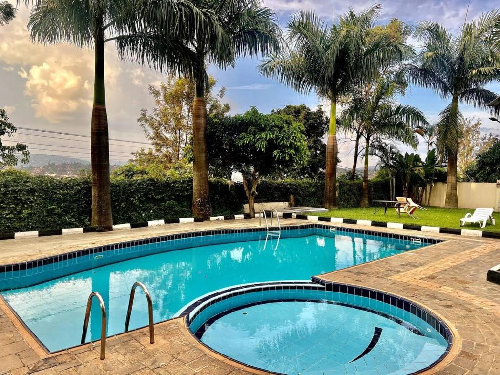a swimming pool with palm trees in the background at Stylish 1-Bedroom Apartment in Kigali