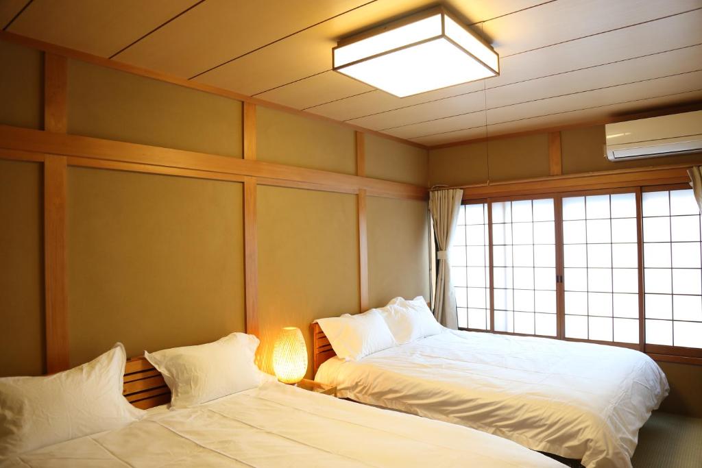 Dos camas en una habitación con ventana. en 雅舍8大阪南海線岸里玉出駅1min新開業一户建貸切100平米可駐車, en Osaka