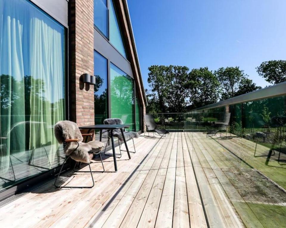a wooden deck with a table and chairs on a building at Nordic Bliss Cozy Villa with Jacuzzi & Sauna in Nørdstebø 