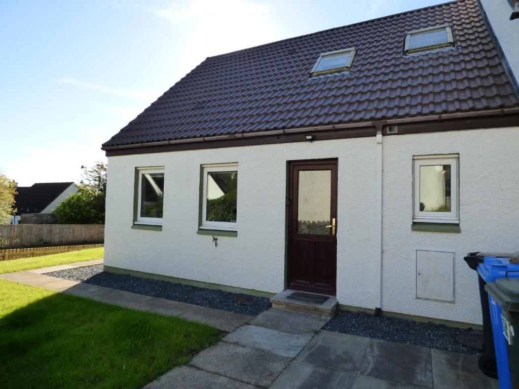 a white house with a door and a yard at Taigh Coig in Gairloch