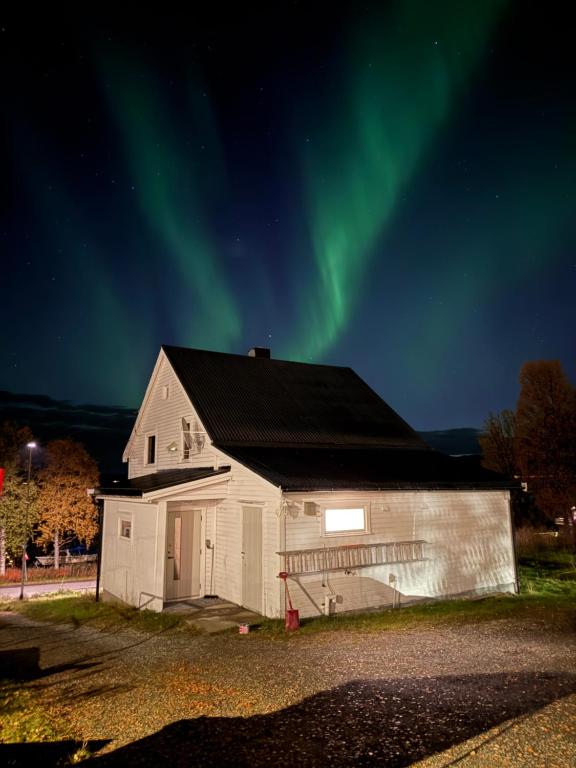Un viejo granero con la aurora en el cielo. en Sigridtunet - 4 bedroom Arctic experiences by the sea, with great opportunities to see the Northern lights dancing just for you!, en Tromsø