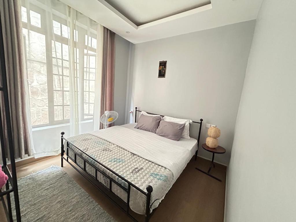 a bedroom with a bed with white walls and a window at Cozy corner in Kigali