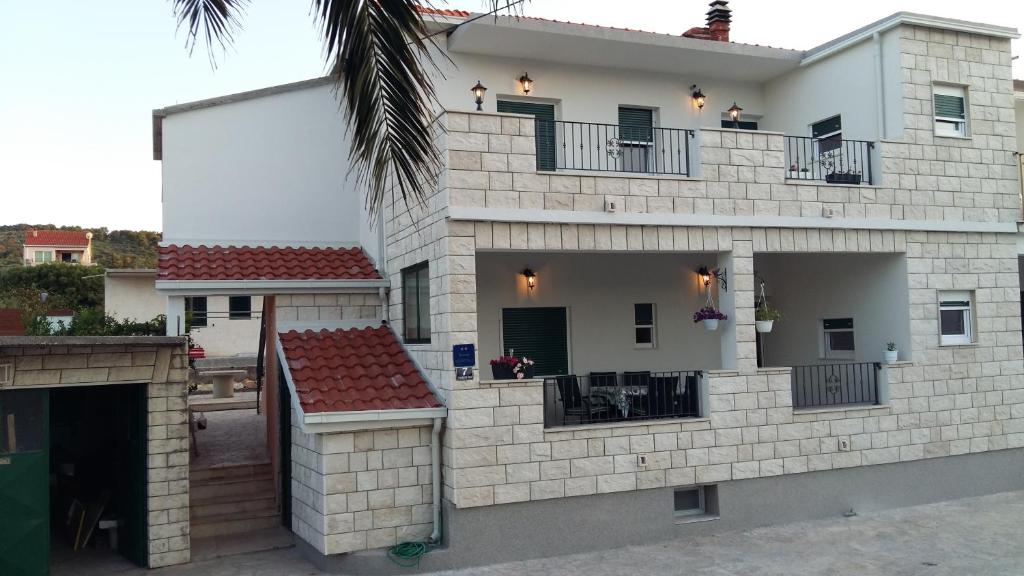 ein weißes Backsteinhaus mit einer Terrasse und einem Balkon in der Unterkunft SAN Apartments in Slatine