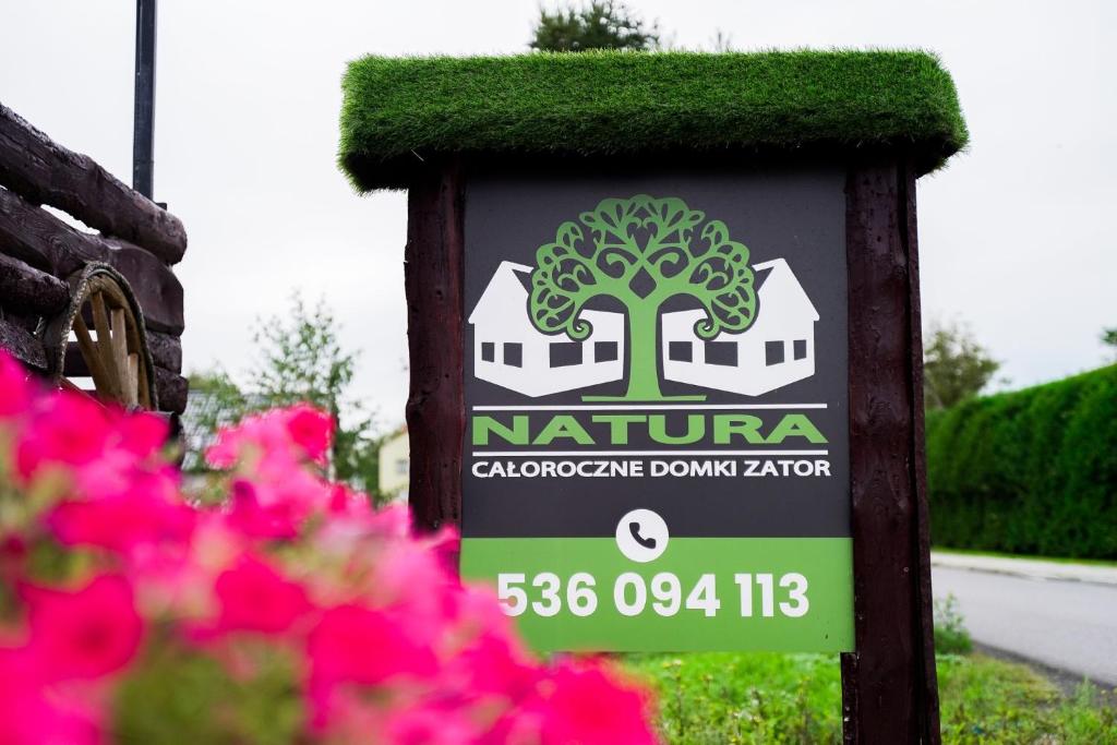 een bord voor een tuin met roze bloemen bij Domki Natura Zator in Graboszyce