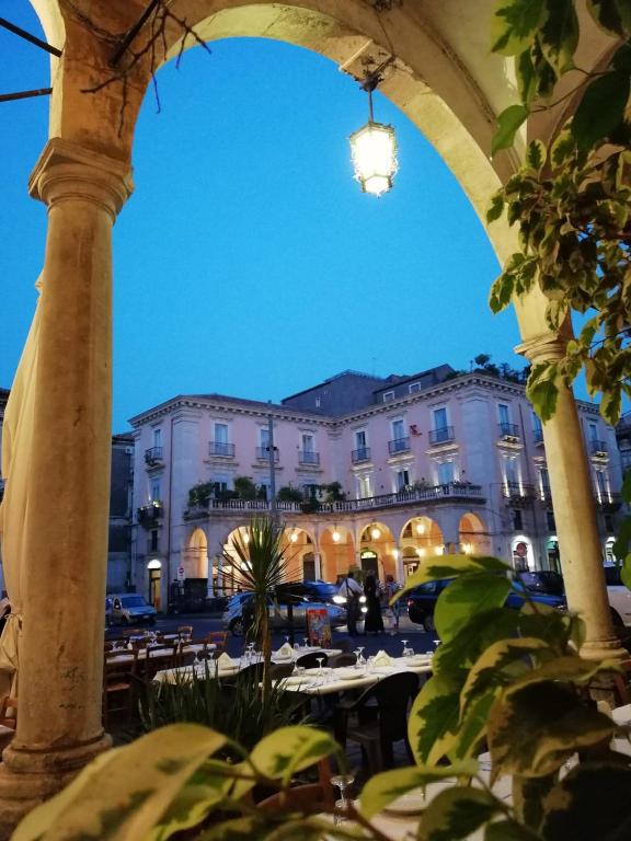 a view of a building from an archway with tables at B&B Piazza Mazzini in Catania