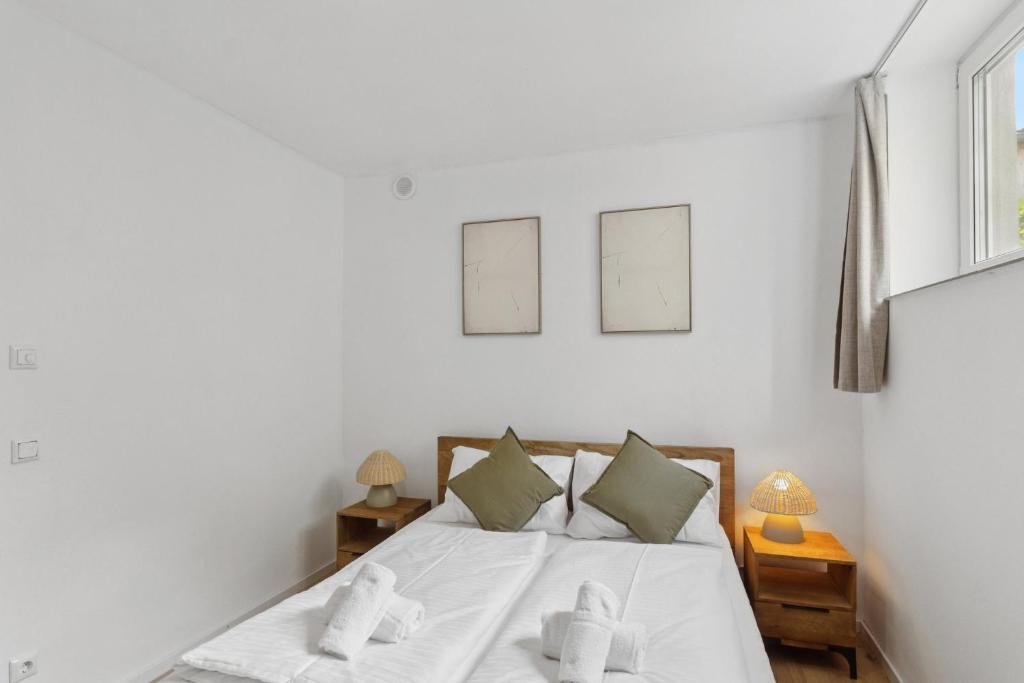 a bedroom with a bed with white sheets and pillows at Terra & Verde Stay in Starnberg