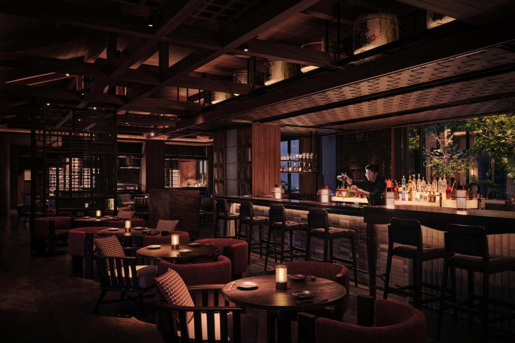 A dimly lit bar-restaurant combines round tables, counter seating, and a long drinks bar.