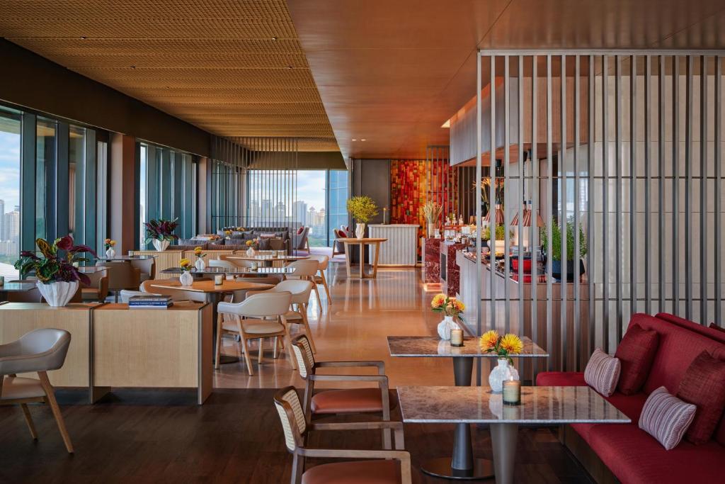 A bright all-day dining room pairs city-facing windows with laid tables and lounge seating.