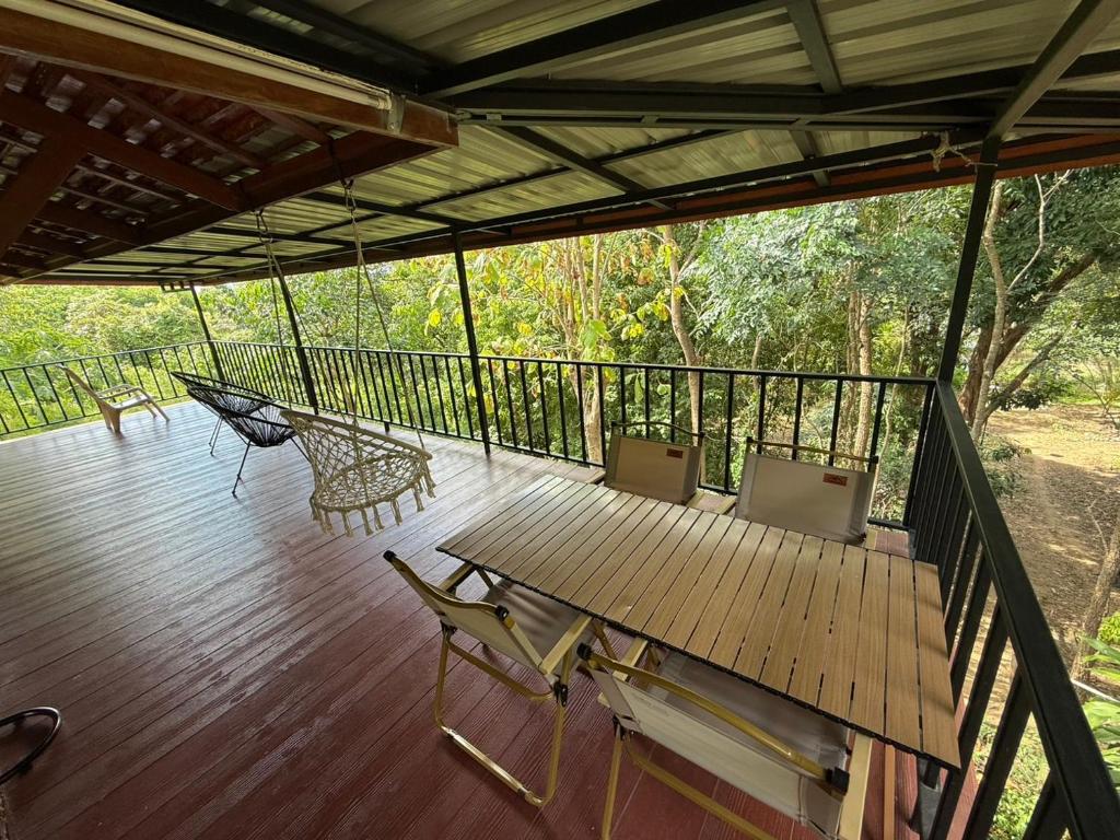 a porch with a hammock and a table and chairs at Serenity by the River in Ban Tha Pong (1)
