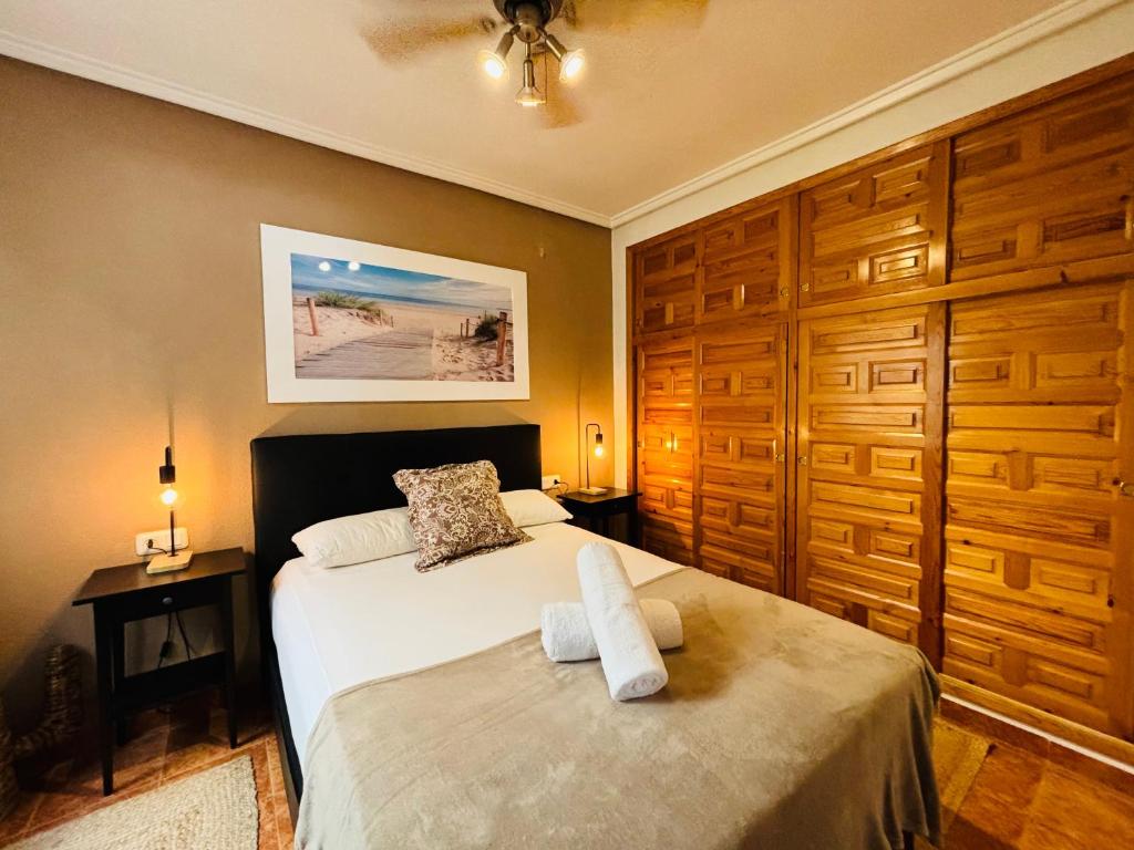 a bedroom with a bed and wooden cabinets at Casa Zeus by SunshineClub in Los Alcázares
