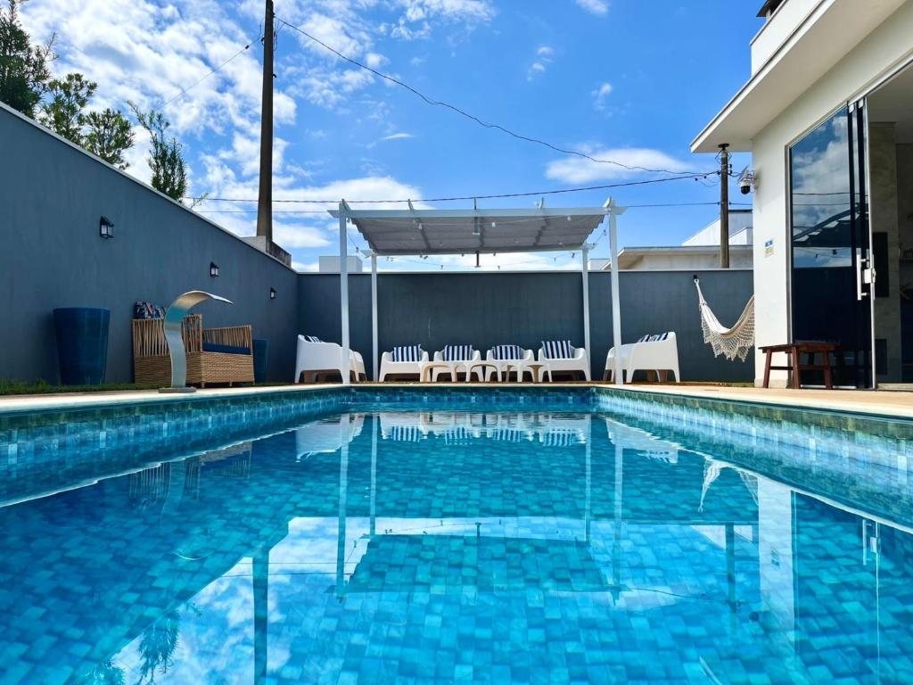 une piscine avec de l'eau bleue devant une maison dans l'établissement Casa dos sonhos, relaxar Ninho Verde 1 com Piscina, à Quadra
