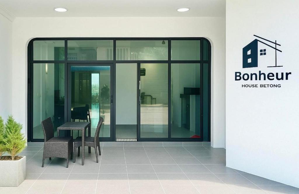 a glass entrance to a building with a table and chairs at bonheurhousebetong in Betong