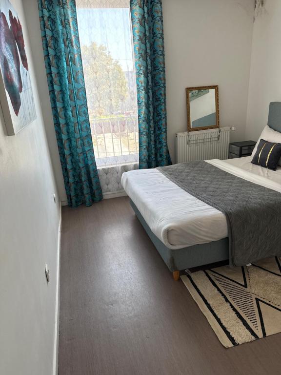 ein Schlafzimmer mit einem Bett mit blauen Vorhängen und einem Fenster in der Unterkunft Chambre familiale lumineuse et spacieuse in Lille