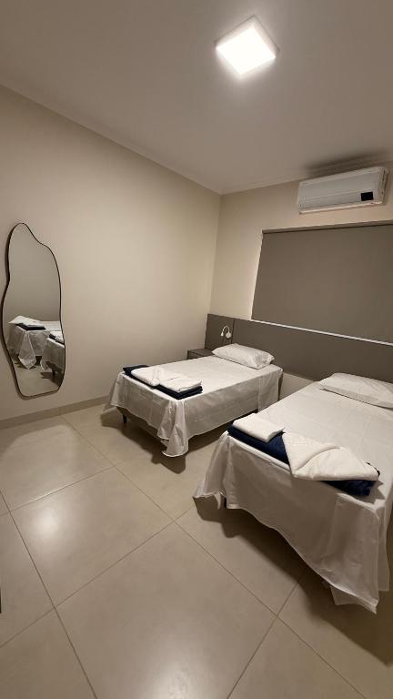 a room with two beds and a mirror on the wall at Loma Sweet Home in Bataguaçu