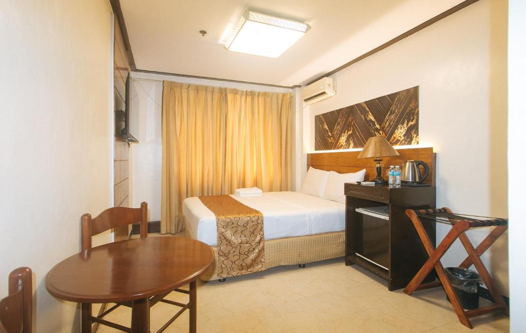 马尼拉The Shilla Philia Hotel by RedDoorz的一间带床和桌子的酒店房间