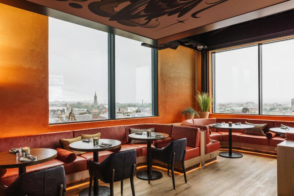 a restaurant with tables and chairs and large windows at The Social Hub Glasgow in Glasgow