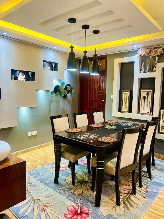 a dining room with a black table and chairs at Maison Princeton in Kampala