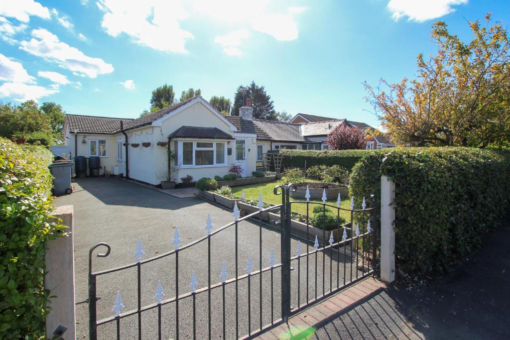 ein Zaun vor einem Haus in der Unterkunft Spacious 3-Bed Bungalow with Parking in Pensby by Rework Accommodation in Birkenhead
