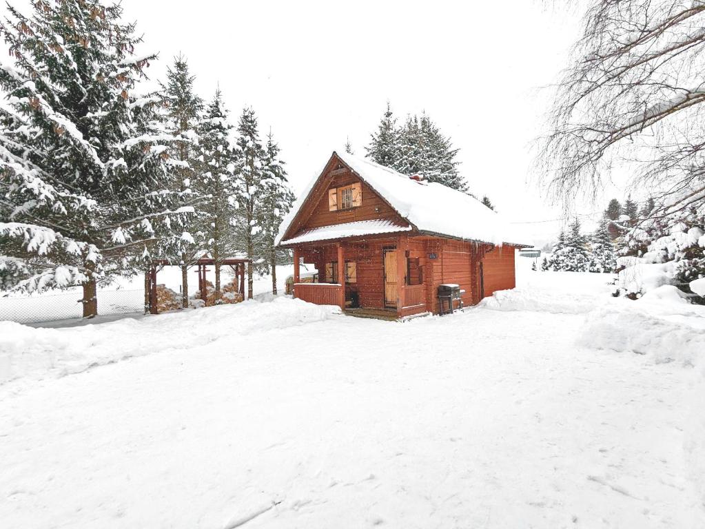 una piccola cabina in legno con neve sul tetto di Chata Wilka Bieszczady - Całoroczny dom z bali z 3 sypialniami i balią a Brzegi Dolne