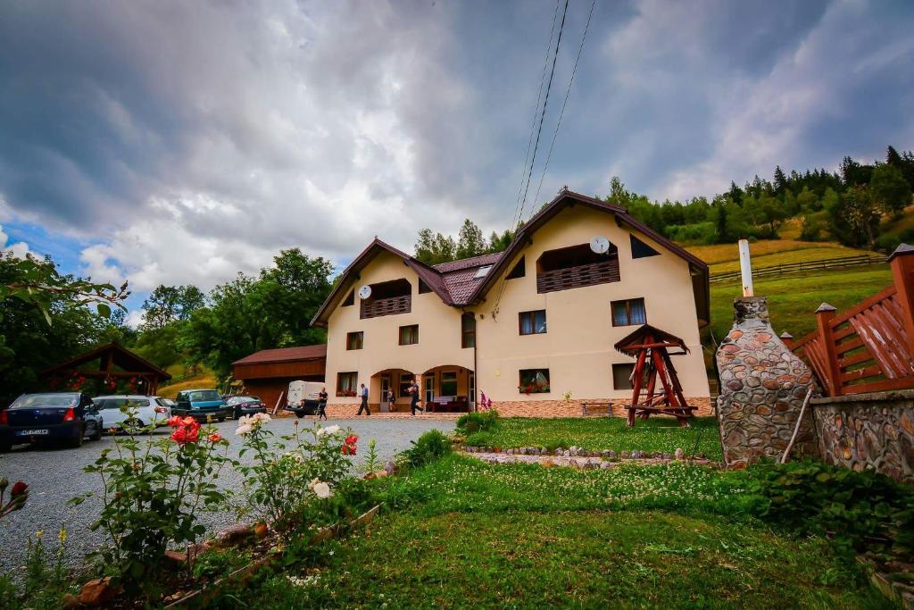 une grande maison avec des voitures garées devant elle dans l'établissement Pensiune Agroturistică Casa Alex, à Baba