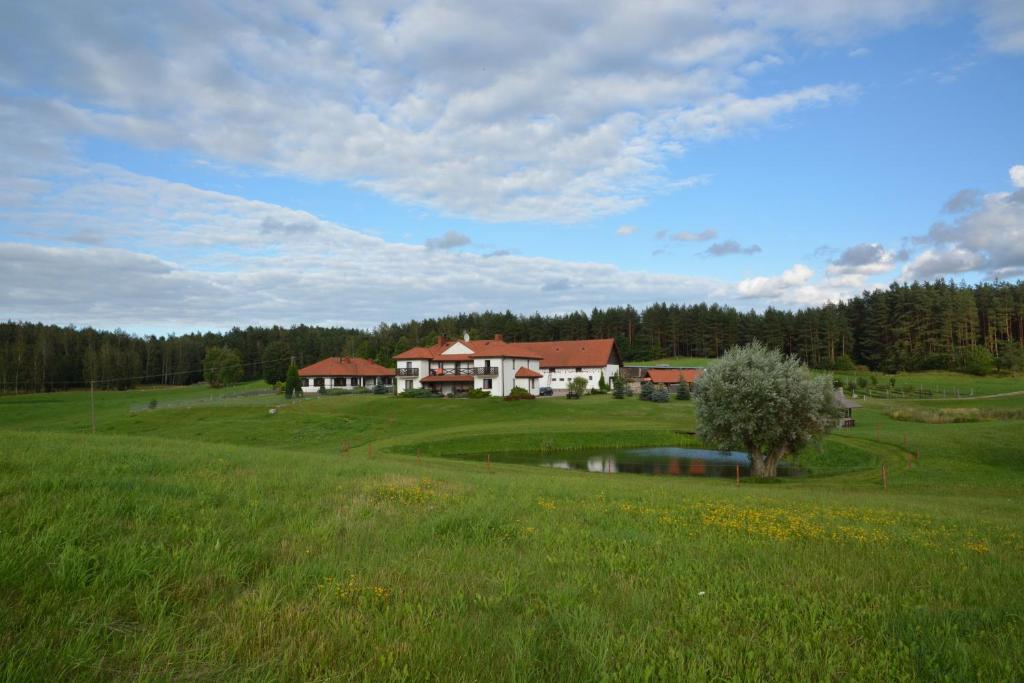 a large green field with a house in the background at Ranczo Pindorówka in Maradki
