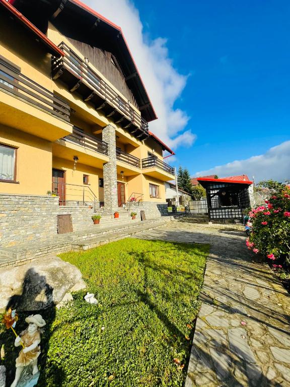 a building with a grassy yard in front of a building at Vila Madisa in Buşteni