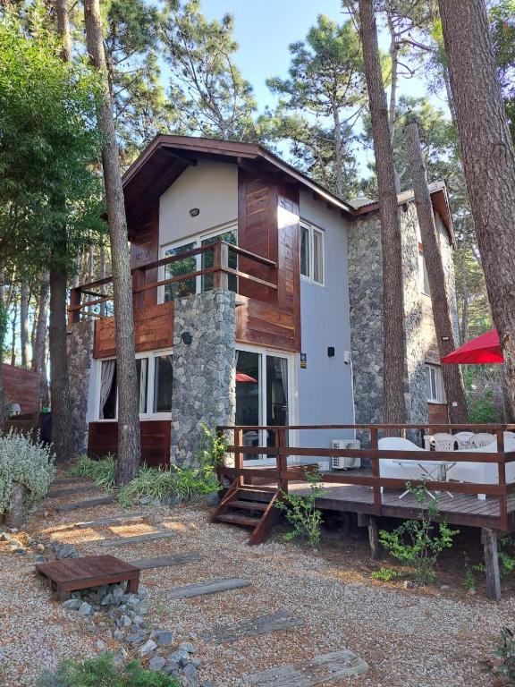 a house in the woods with a porch and benches at Amura in Mar Azul