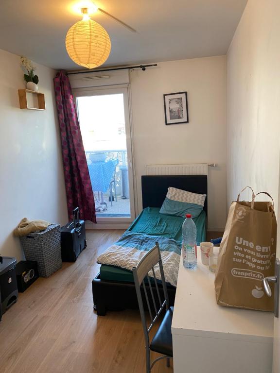 a living room with a bed and a table with a bag at Super chambre avec bureau in Courcouronnes