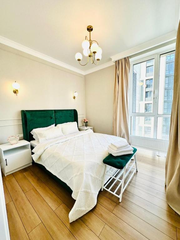 a bedroom with a large bed and a chandelier at Komfort City Residential Fam Luxe Complex with Mountain View in Zhezdi