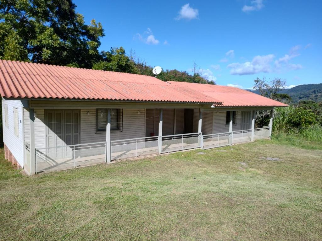 una pequeña casa con techo rojo en un campo en Chalé Paraíso Da Serra 02, en Gramado