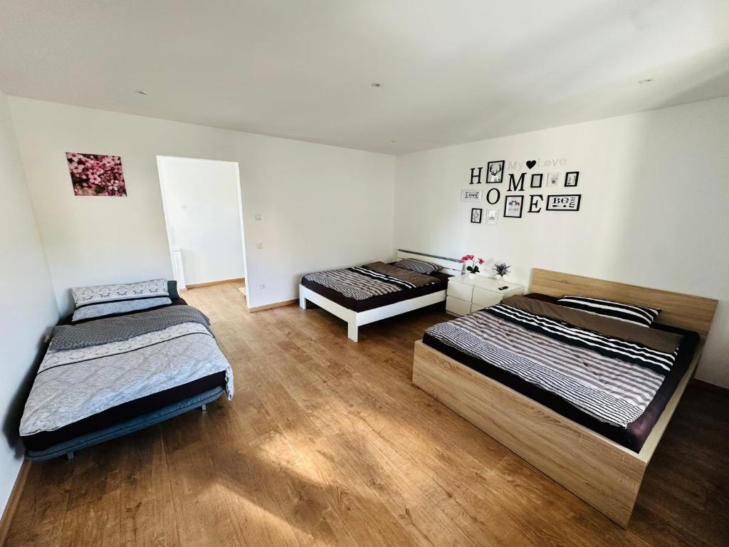two beds in a room with wooden floors at Große 2 Ferienwohnung Gästehaus NEUBAU Merzig 100 m2 in Merzig