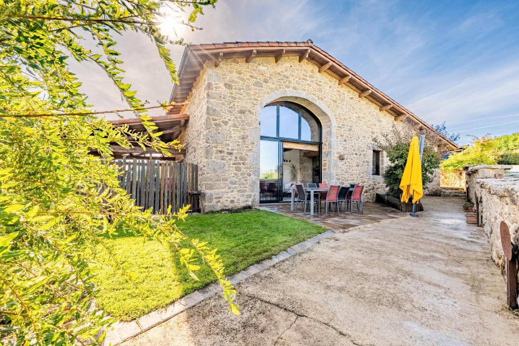 a brick house with a patio and a yard at Gîte Le Bouton D'or 8min Puy du Fou in Chambretaud