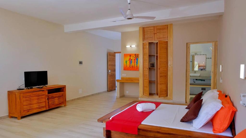 a bedroom with a bed and a tv on a dresser at Résidence Sarimanok in Nosy Be