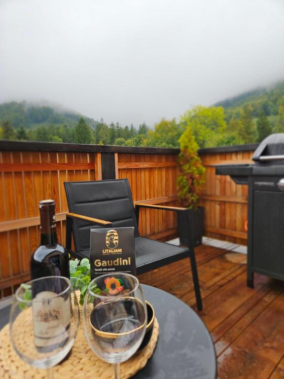 a table with a bottle of wine and glasses on a deck at Chata u lanovky Pustevny in Trojanovice
