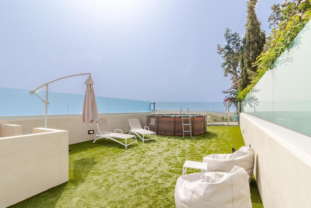 an outdoor patio with grass and a table and chairs at Bungalow Einstein Xej in San Bartolomé