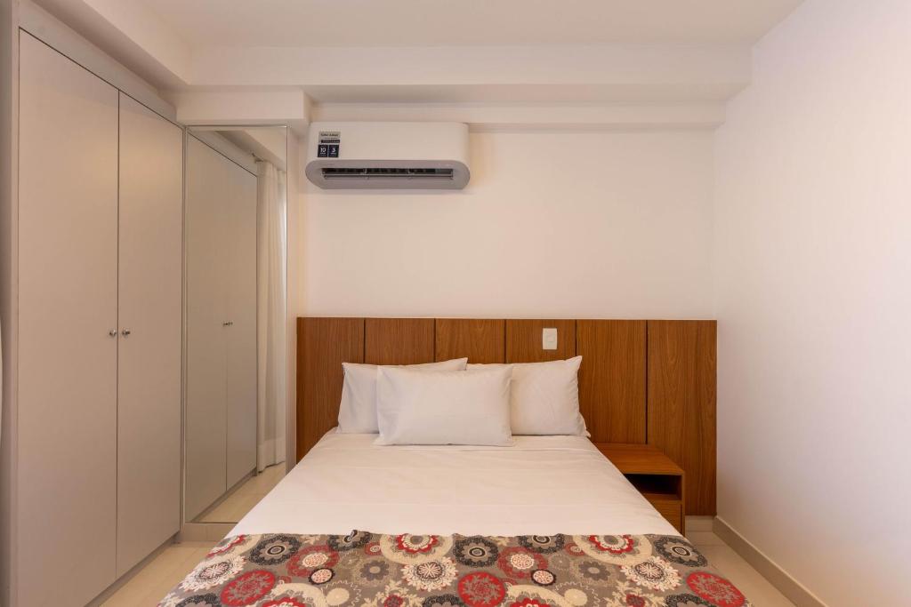 ein Schlafzimmer mit einem Bett mit einer weißen Tagesdecke in der Unterkunft Venice Park Hplus Long Stay in Brasilia