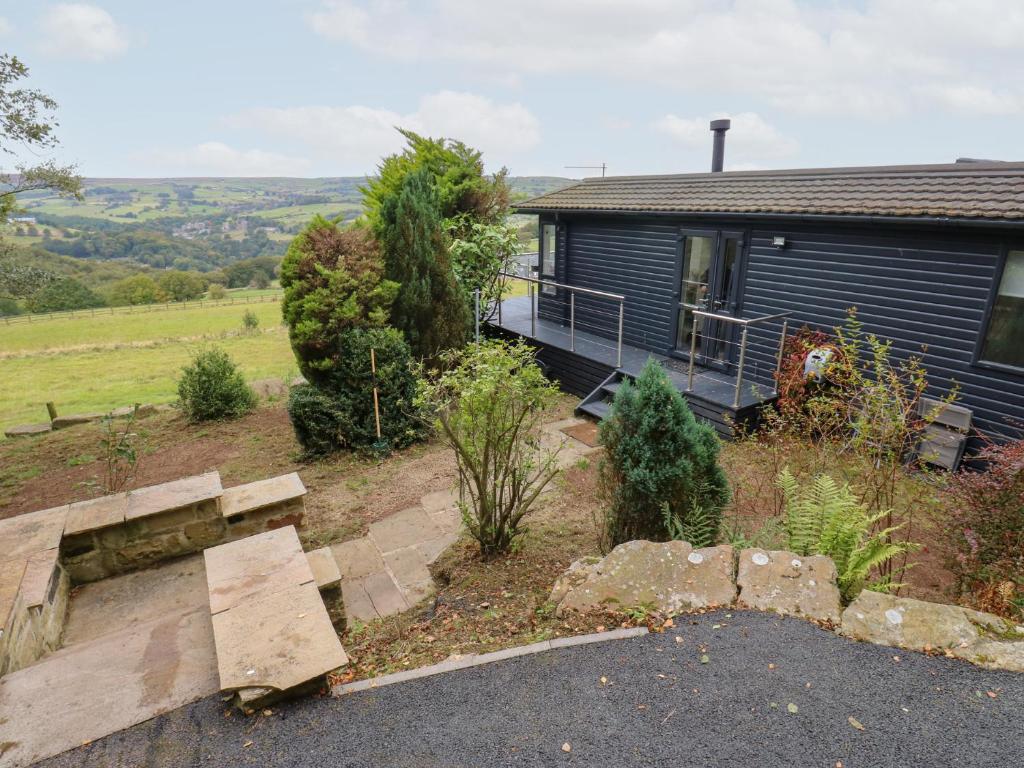 a blue house with a porch and a garden at John's Folly in Sowerby Bridge