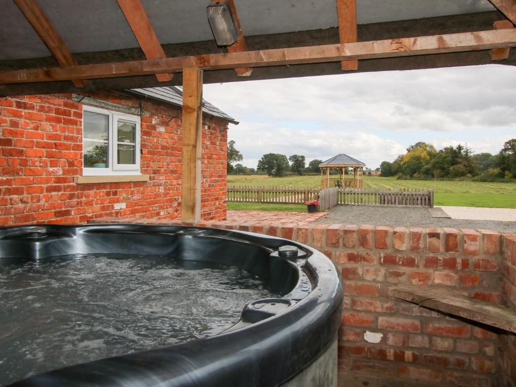 a hot tub outside of a brick building at Millstone Cottages - Millstone Cottage in Shrewsbury