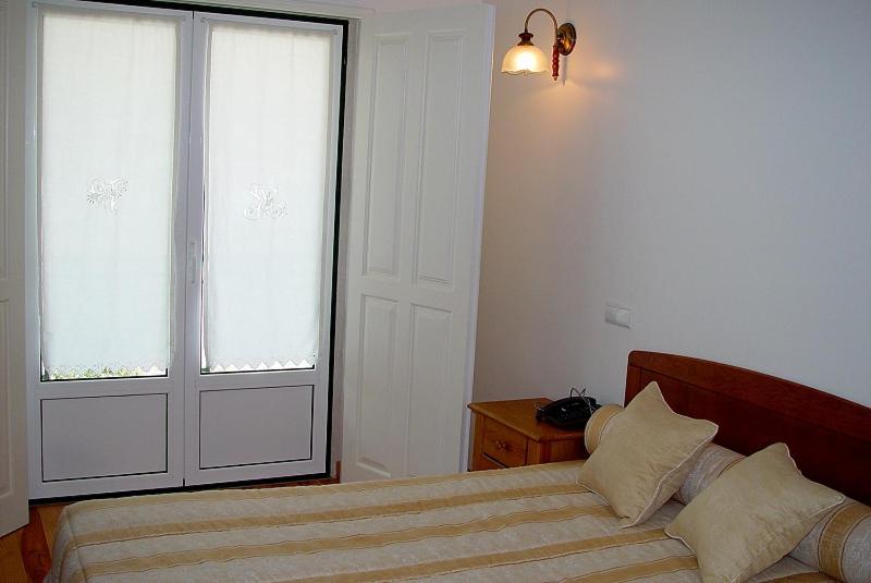 a bedroom with a bed and a large window at Residencial Valinho in Mendiga