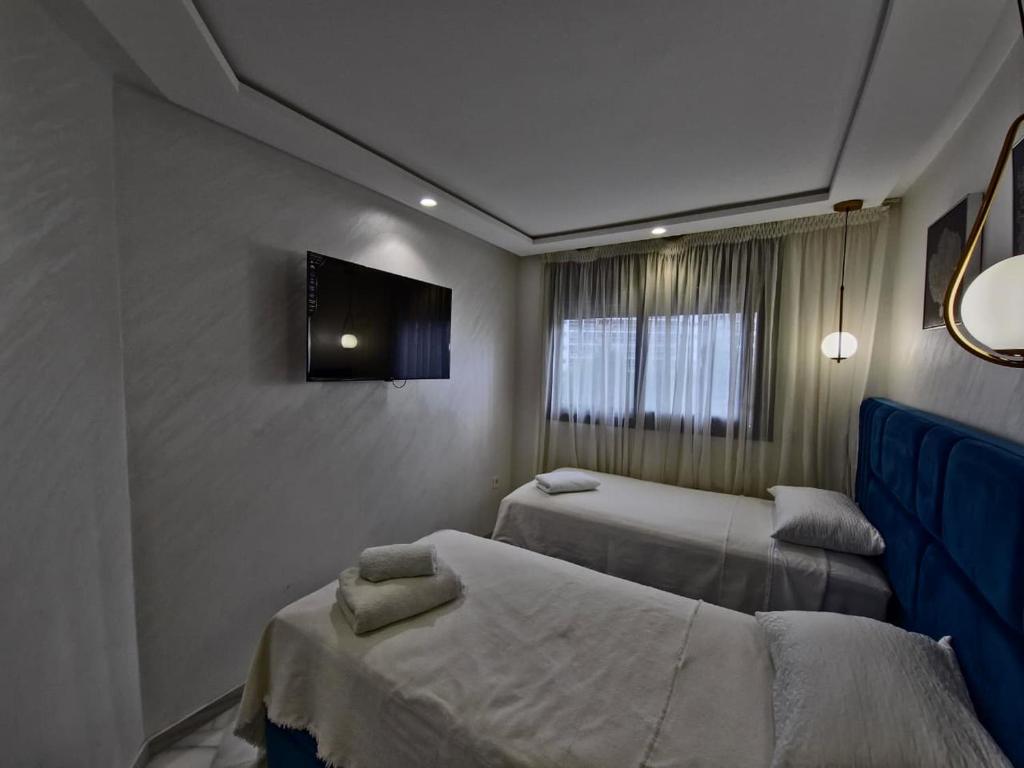 une chambre avec deux lits et une télévision au mur dans l'établissement TANGERSUITE FAMILY MARINA BAy, à Tanger