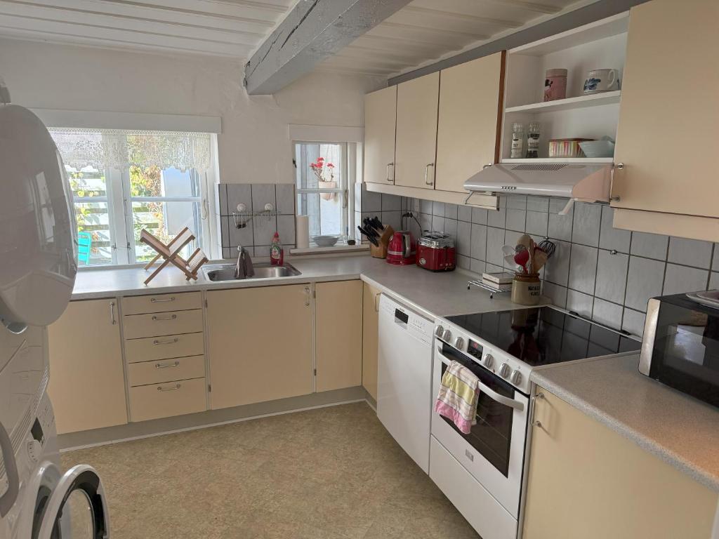 una cocina con armarios blancos y electrodomésticos blancos en Historical Townhouse, en Aabenraa