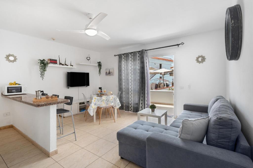 a living room with a blue couch and a kitchen at Sunset Lux Las Floritas in Playa de las Americas