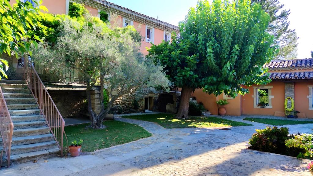 un patio de una casa con árboles y escaleras en Le Barry, en Tulette
