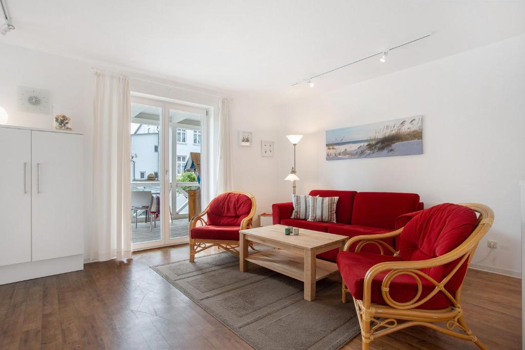 a living room with a red couch and two chairs at Villa Sonneck - Apartment 3 in Ostseebad Sellin