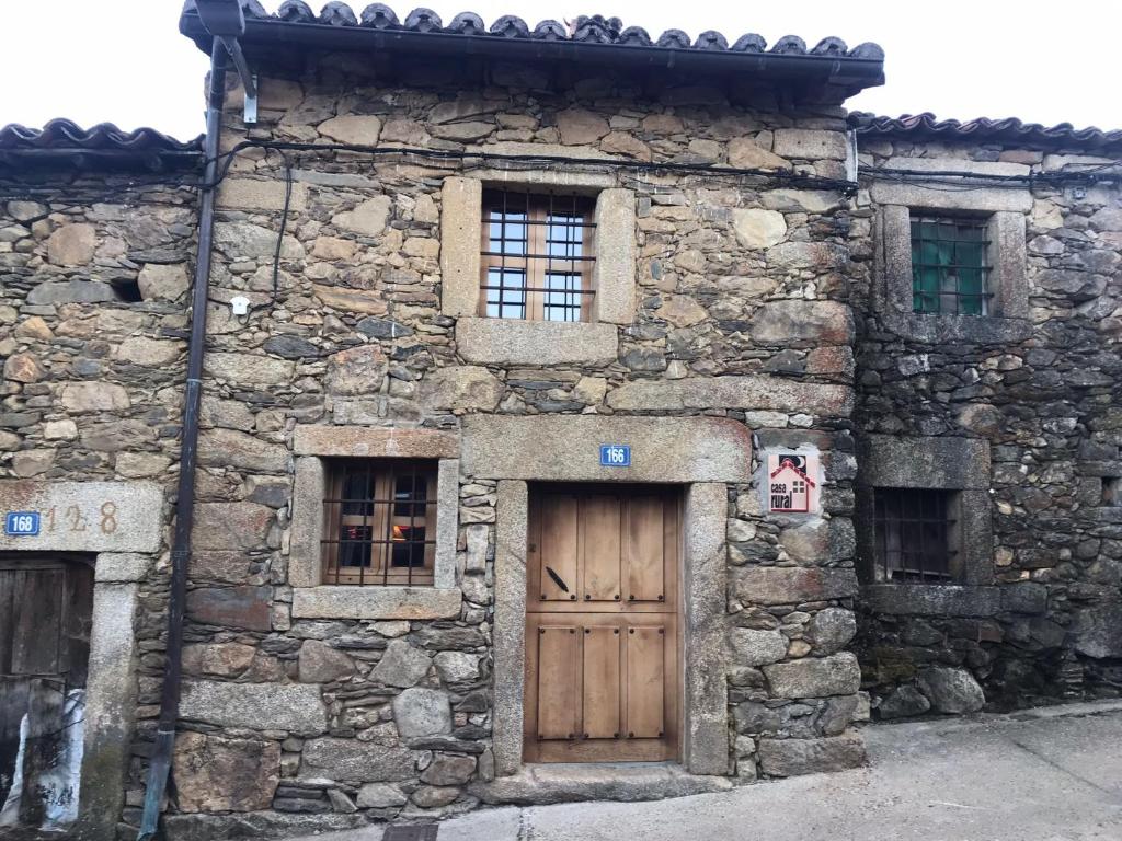an old stone building with a wooden door and windows at La Plazuela - Navalguijo in Navalguijo