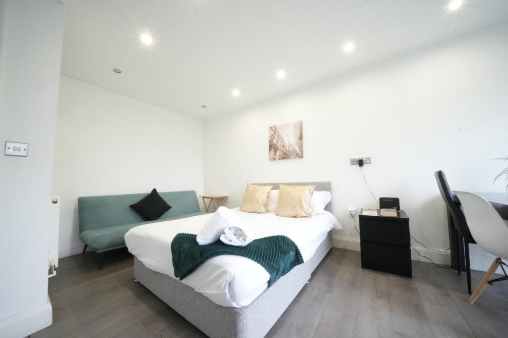 a white bedroom with a bed and a chair at The Hatton Rooms in New Bedfont