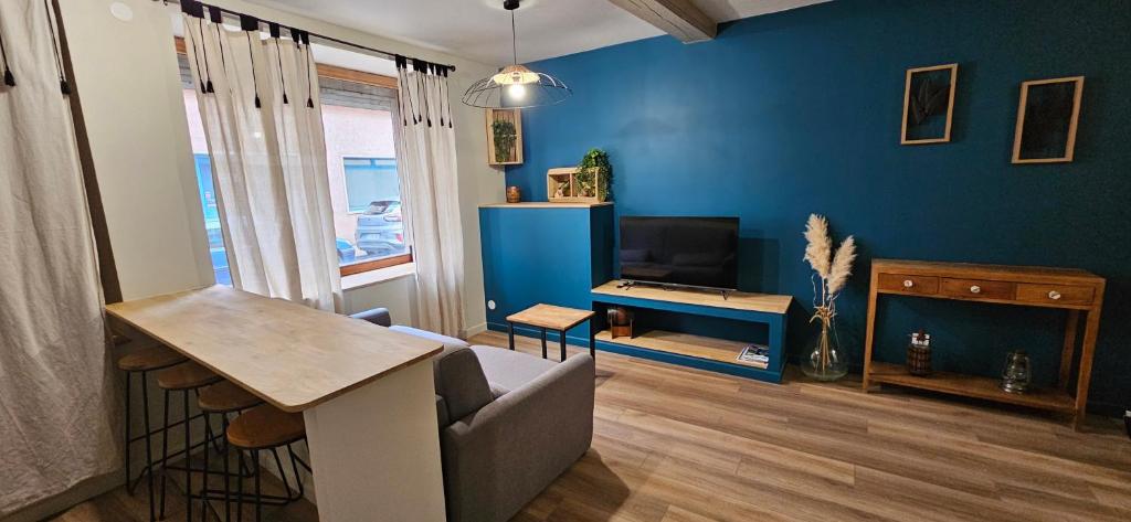 - un salon avec des murs bleus, un canapé et une télévision dans l'établissement Charmant appartement au cœur du centre historique, à Beaujeu