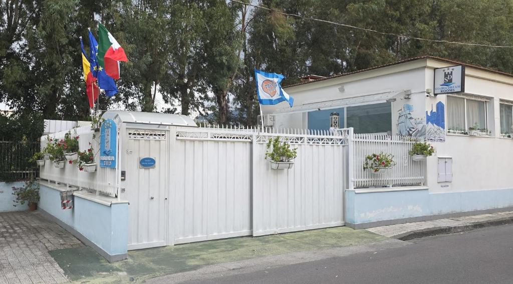 a white house with a white fence and flags at Stabia Dream Rooms in Castellammare di Stabia
